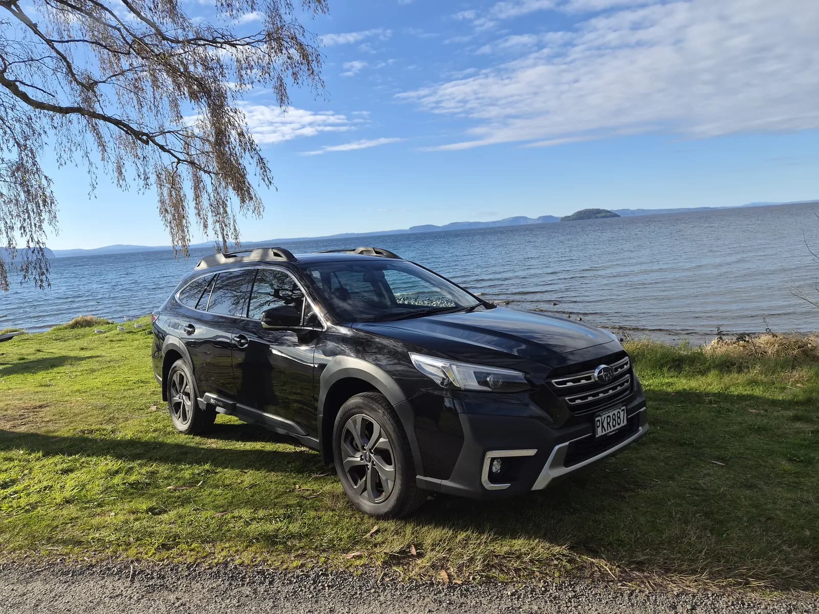 Black 2022 Subaru Outback by the lake, front three-quarter view